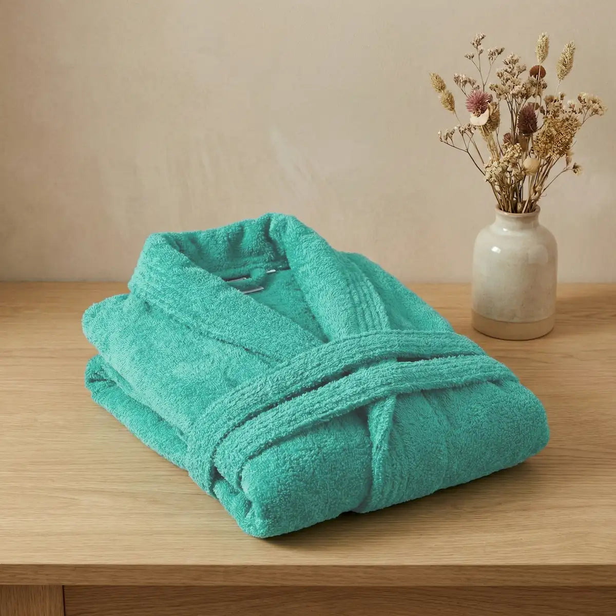 Primer plano del tejido de algodón peinado del albornoz turquesa, mostrando su suavidad y acabado premium sin impurezas.