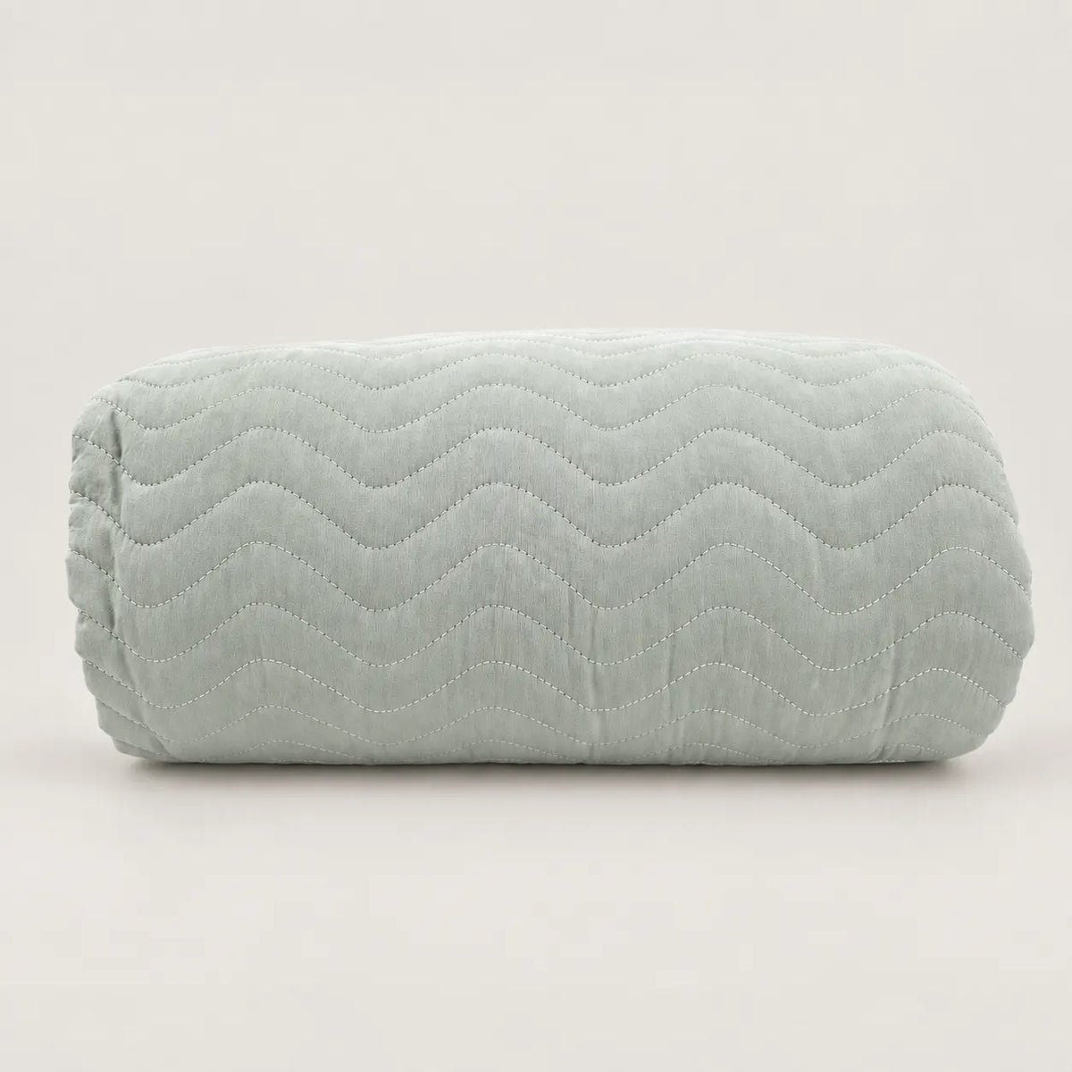 Cubrecama ligero de verano en tono verde claro liso plegado, destacando su suave relieve cosido en zig zag.