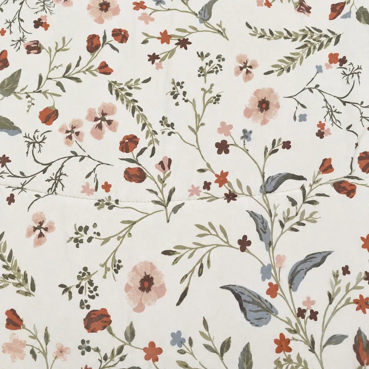 Close-up of the floral print with leaves and flowers in warm earthy tones on a light background.