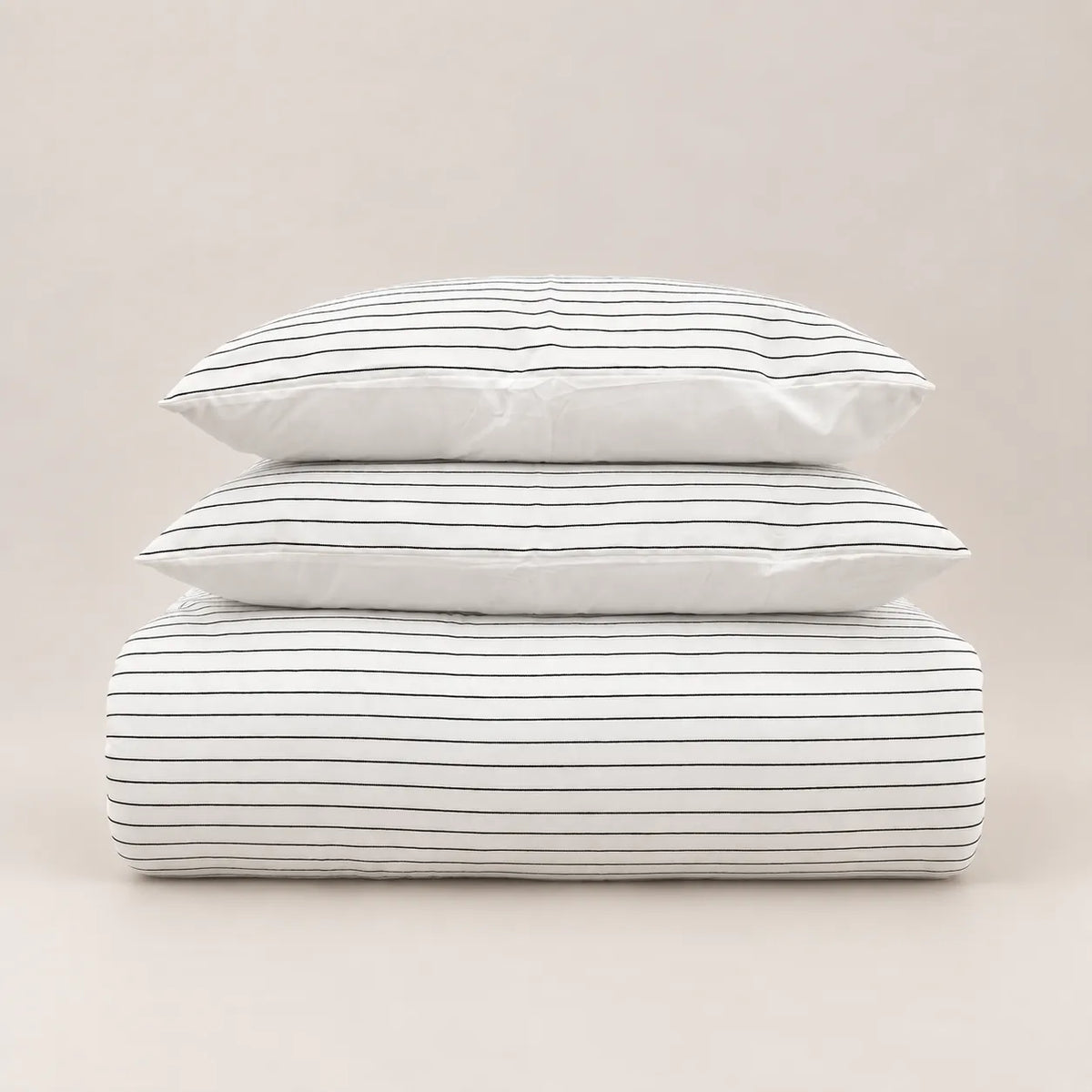 Winter-Bettdecke mit feinem Jacquard-Streifenmuster, ordentlich gefaltet mit zwei passenden Kissenbezügen.