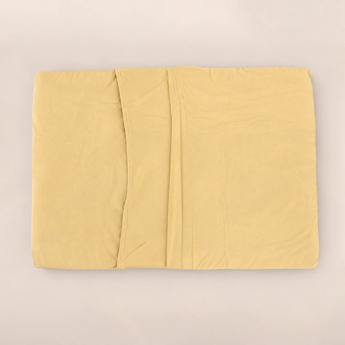 Parte posterior con solapa de la funda de almohada en microfibra lisa tono mostaza cálido.