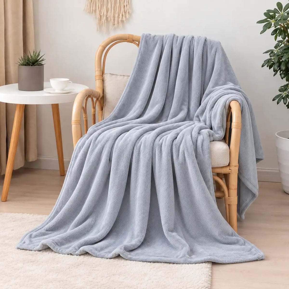 Manta polar fina y extra suave de color liso gris claro azulado extendida sobre una butaca, aportando serenidad y confort al salón de Oma Home.